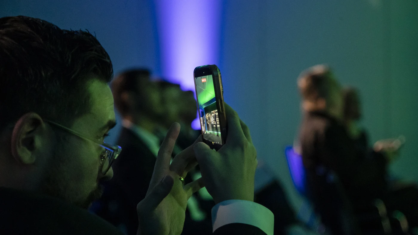 Ein Gast hält die Preisverleihung mit dem Smartphone fest